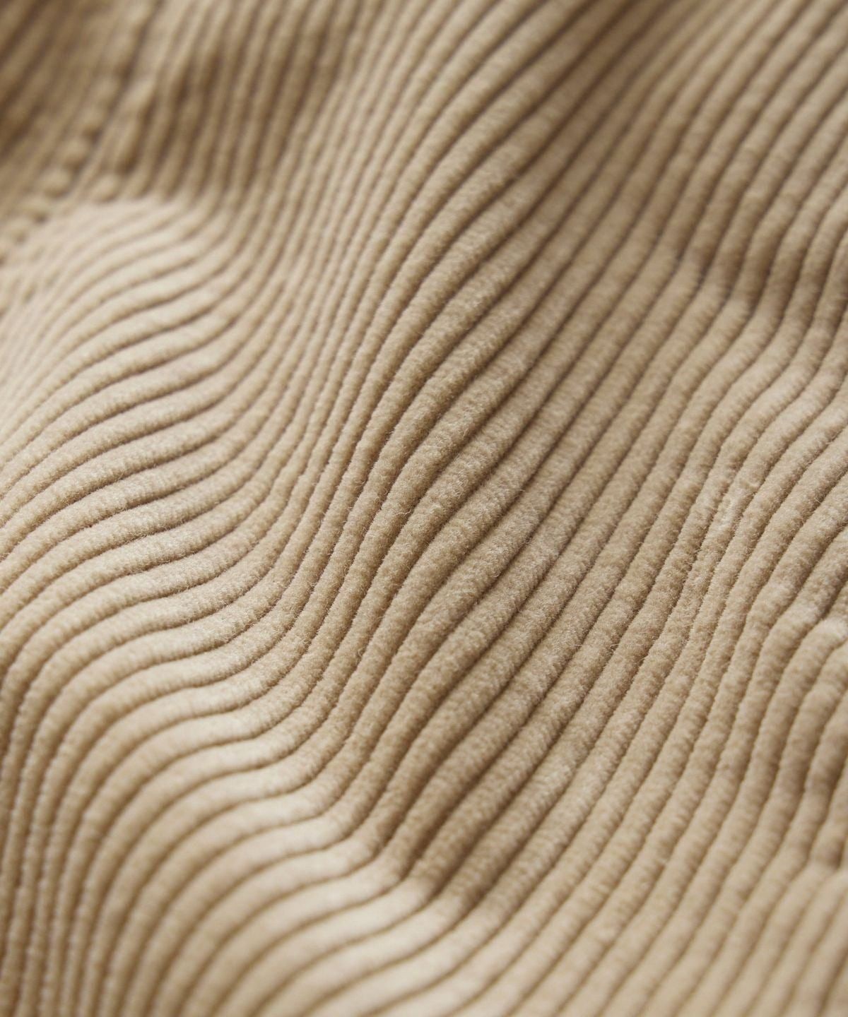 Macro of ribbed corduroy, the wales curving in raking light.