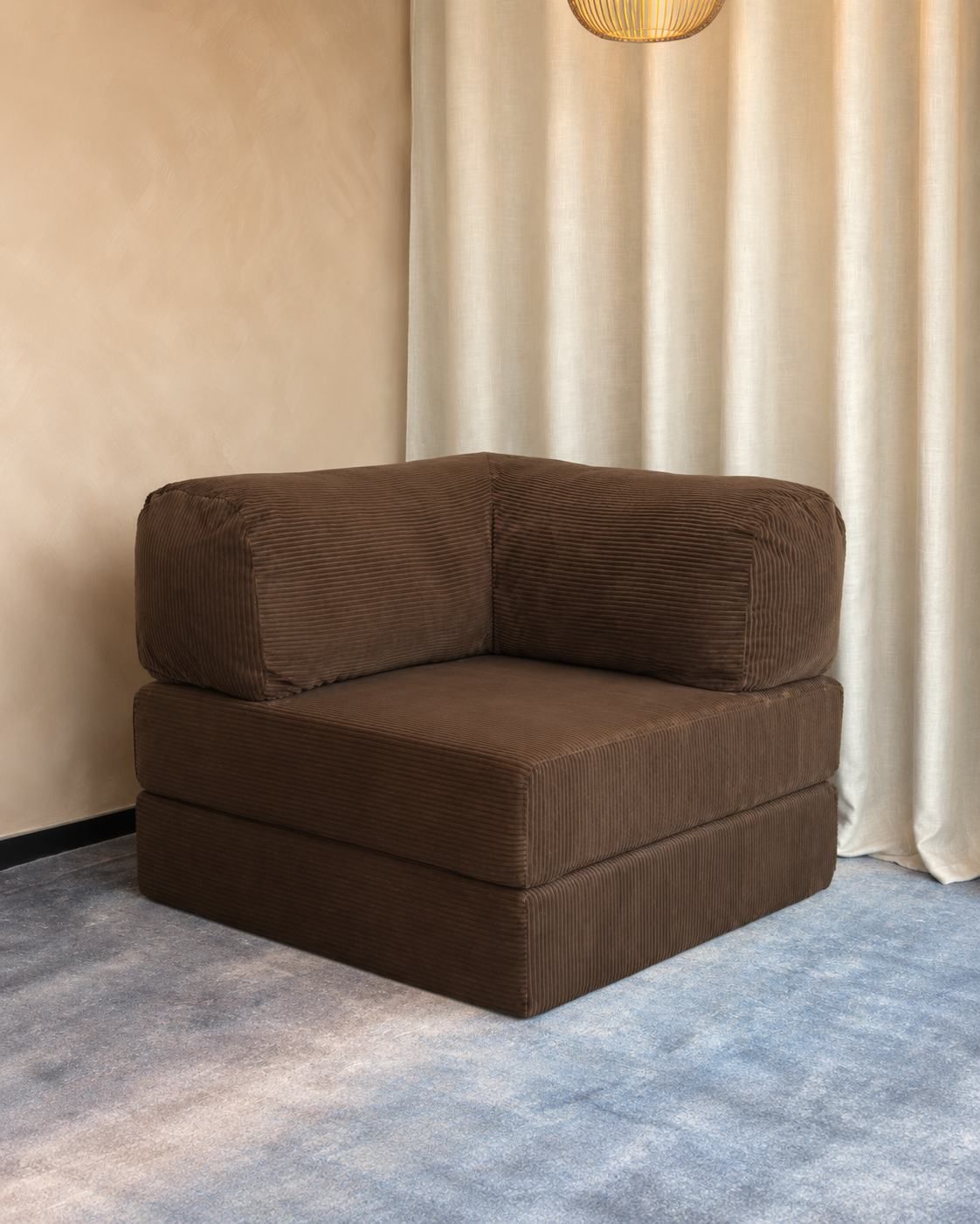 The cocoa brown Cloud Single in a reading corner beside a window.
